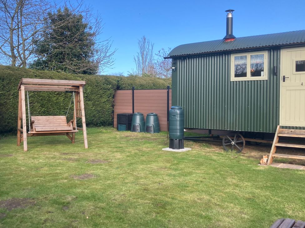 A garden with a shepherd hut and swing at Twit Twoo Shepherds Hut North Somercotes