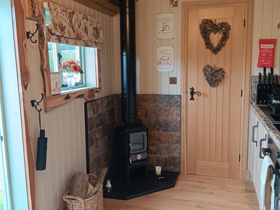 A kitchen area with a wood stove and window at Twit Twoo Shepherds Hut in North Somercotes