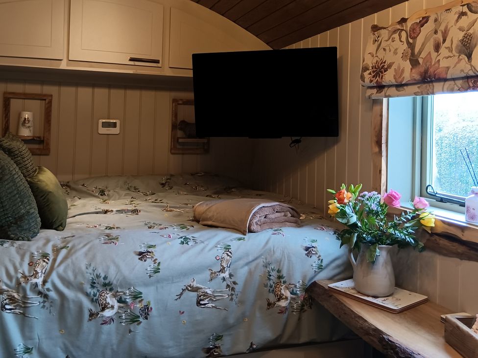 A bedroom with a bed and television at Twit Twoo Shepherds Hut North Somercotes