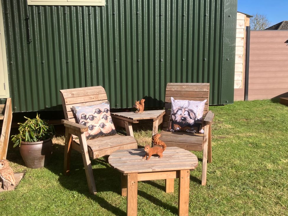 A garden setup with wooden chairs and table at Twit Twoo Shepherds Hut North Somercotes