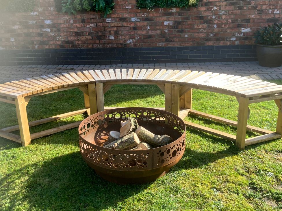 A bench and fire pit with logs at Twit Twoo Shepherds Hut in North Somercotes