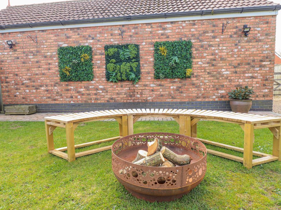 A garden with a fire pit and benches at Twit Twoo Shepherds Hut in North Somercotes