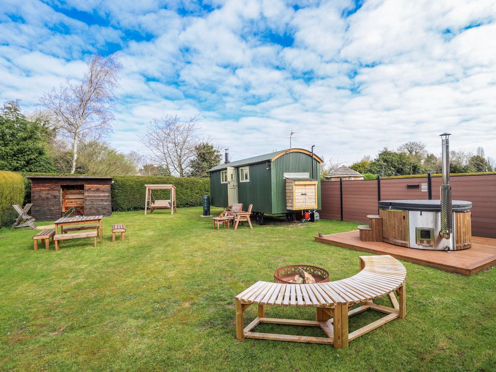 A garden with a shepherd's hut and a hot tub at Twit Twoo Shepherds Hut North Somercotes