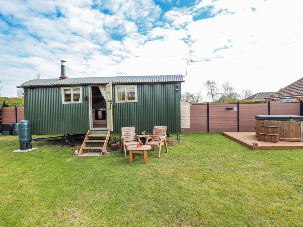 A shepherd hut with outdoor seating and a hot tub at Twit Twoo Shepherds Hut North Somercotes