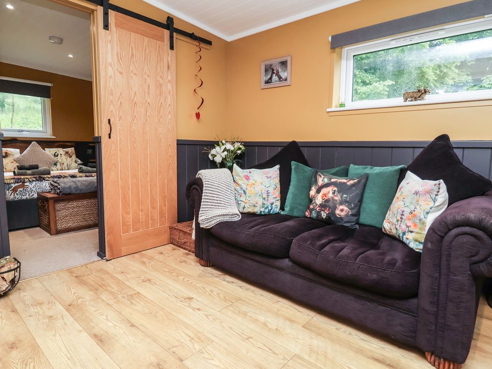 A living room with a sofa and a sliding door at Owls Nest Lodge South Molton