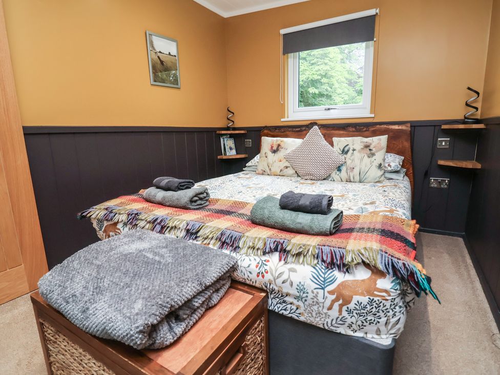 A bedroom with a bed and shelves at Owls Nest Lodge South Molton