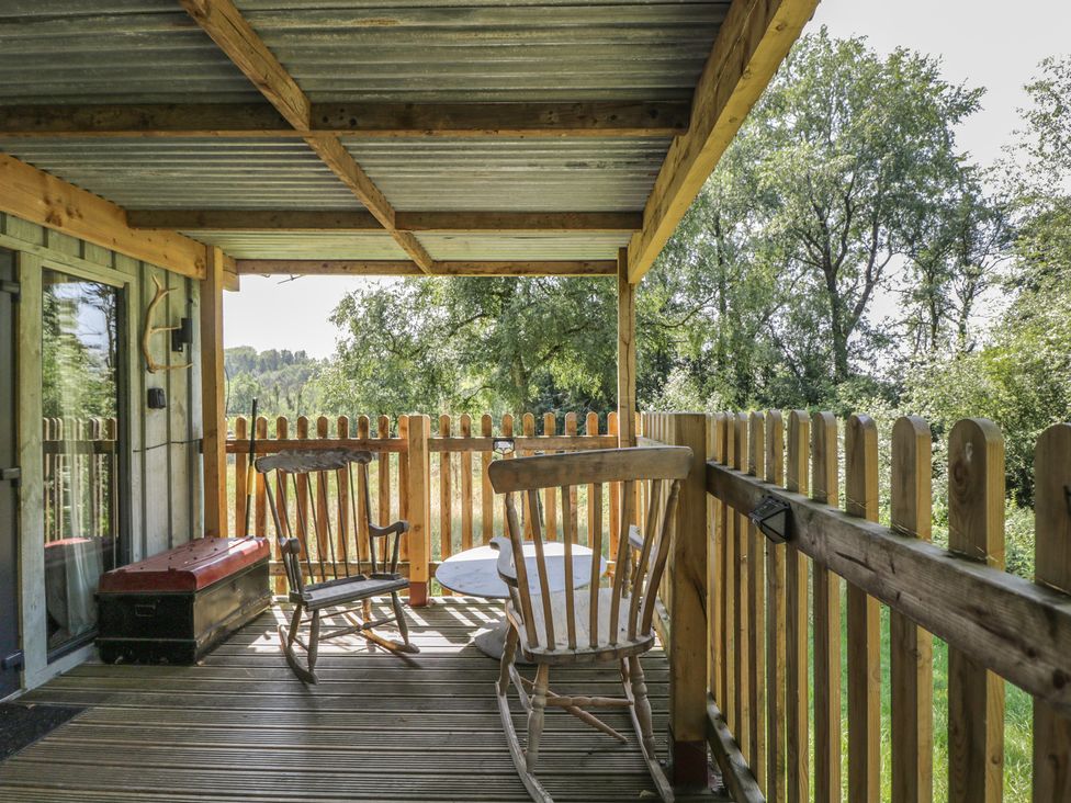 A porch with two rocking chairs and a table at Owls Nest Lodge in South Molton