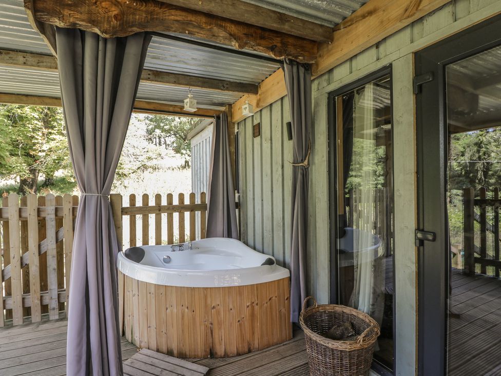 An outdoor area with a hot tub and curtains at Owls Nest Lodge South Molton