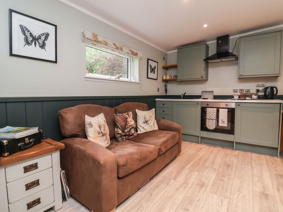 A living room with a sofa and kitchen in Robins Nest Lodge South Molton