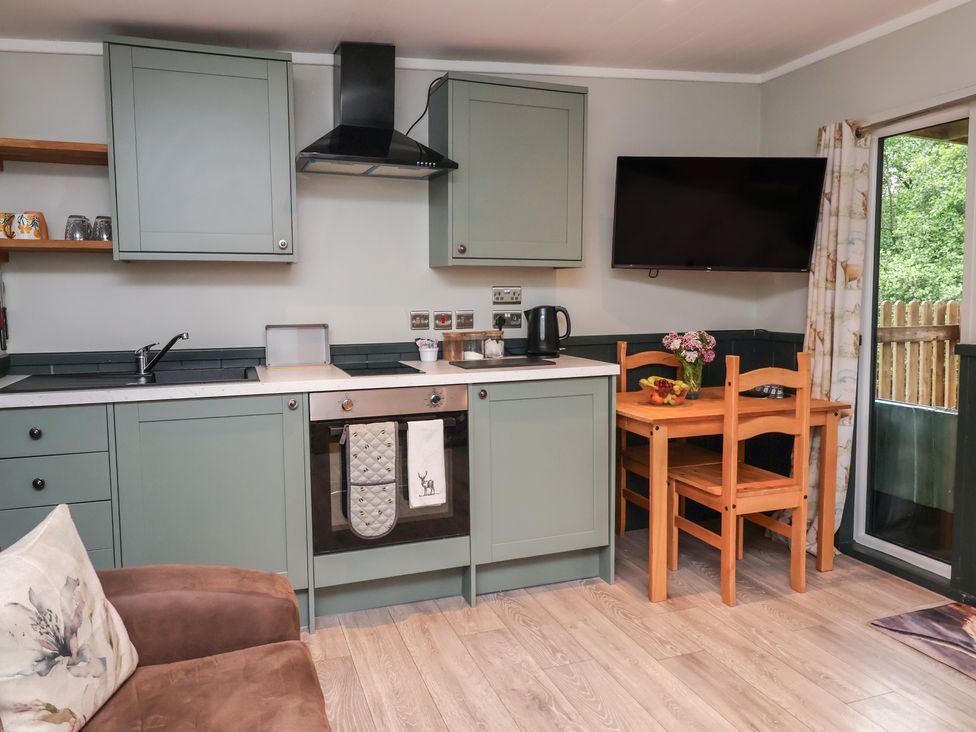 A kitchen with cabinets, appliances, and a table at Robins Nest Lodge South Molton