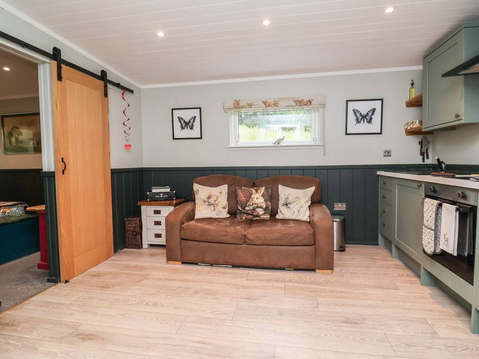 A living room with a sofa and kitchen units at Robins Nest Lodge in South Molton