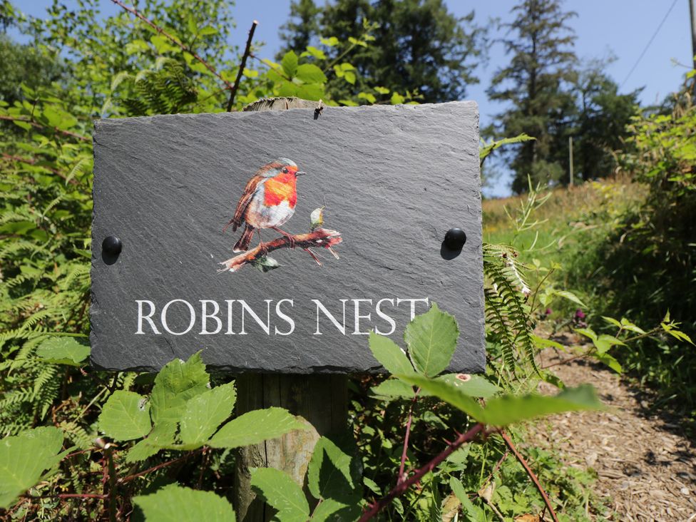 A sign with a bird illustration and text at Robins Nest Lodge South Molton