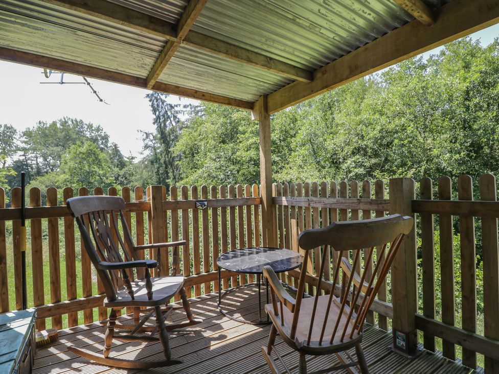 A deck with two rocking chairs and a table at Robins Nest Lodge South Molton