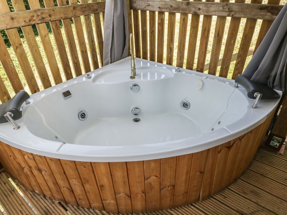 A hot tub with wooden paneling in an outdoor area at Robins Nest Lodge in South Molton