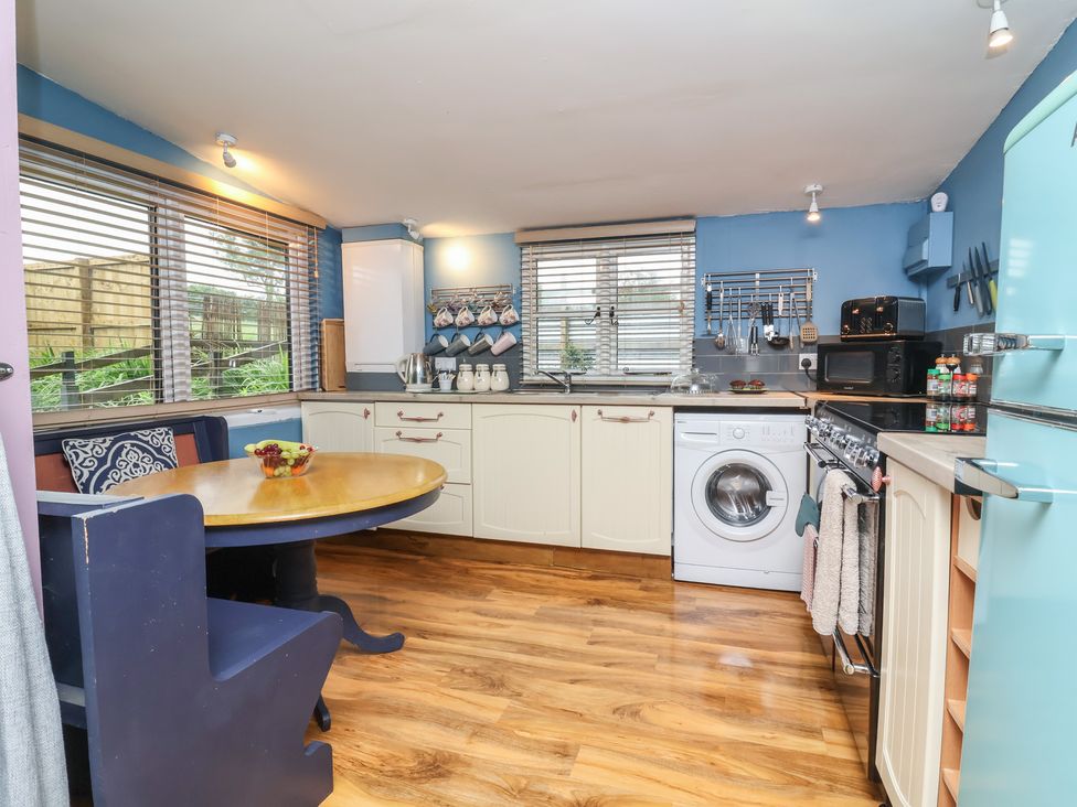 A kitchen with appliances and a table at Hedgehogs Lodge in South Molton