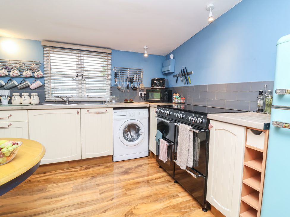A kitchen with a washing machine and oven at Hedgehogs Lodge in South Molton