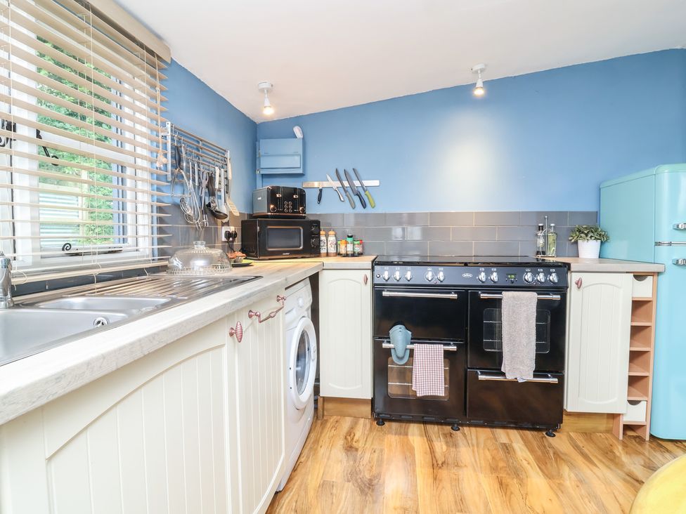 A kitchen with a sink, oven, washing machine and refrigerator at Hedgehogs Lodge South Molton