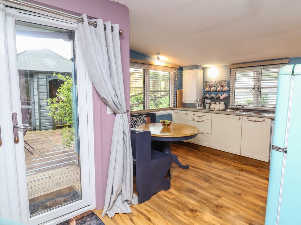 A kitchen with a dining table and refrigerator at Hedgehogs Lodge in South Molton