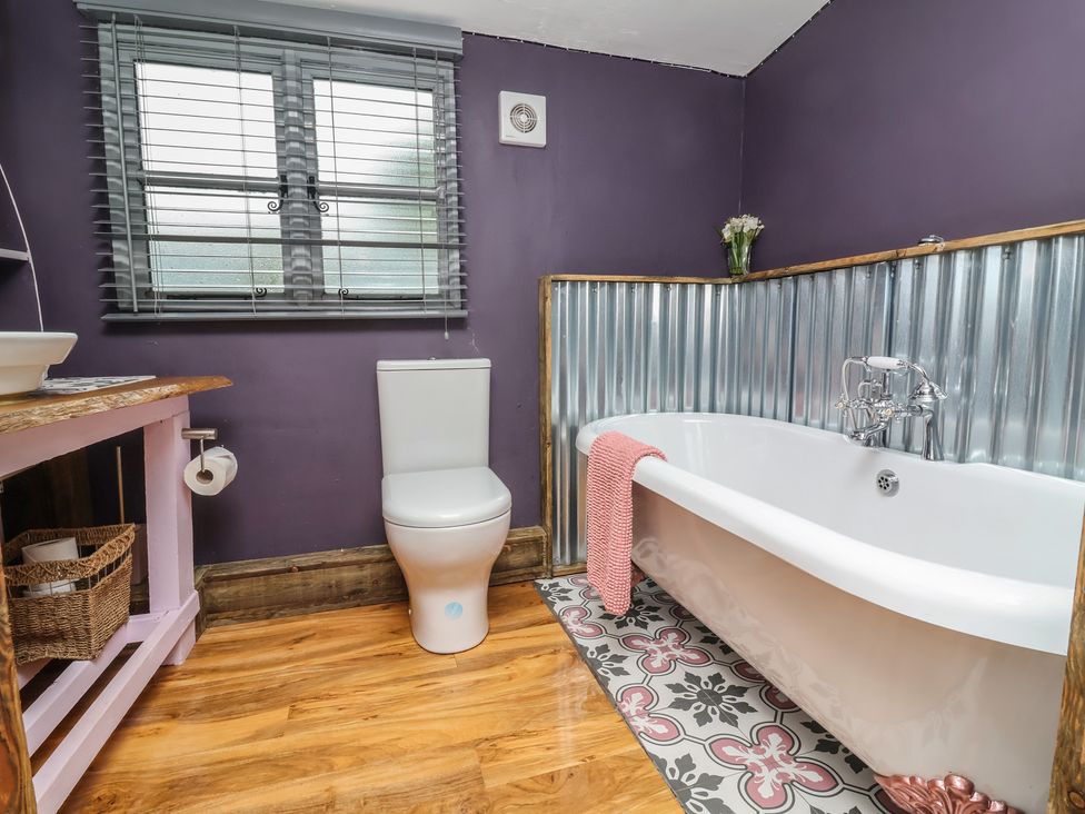 A bathroom with a toilet, bathtub, and sink at Hedgehogs Lodge in South Molton