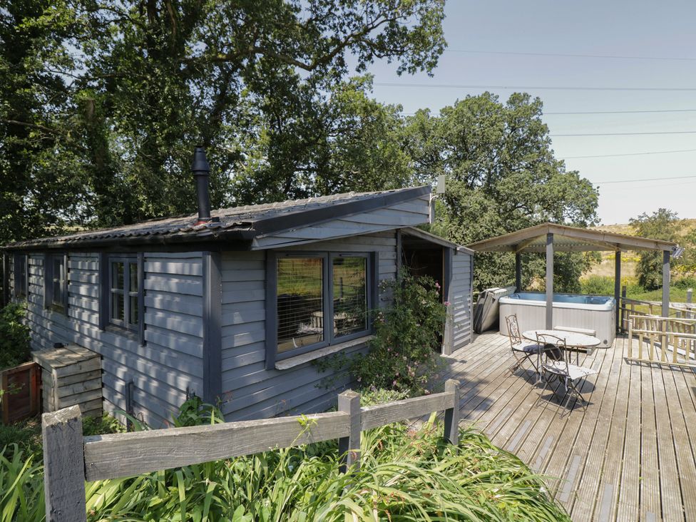 A cabin with a hot tub and seating area at Hedgehogs Lodge in South Molton