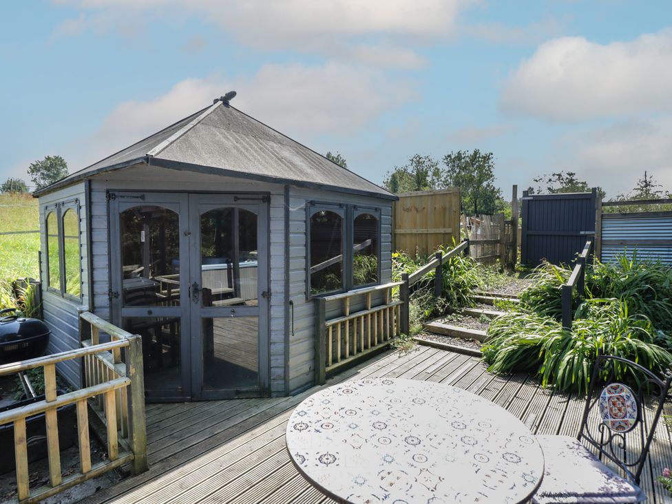 A gazebo with decking and table in the garden at Hedgehogs Lodge South Molton