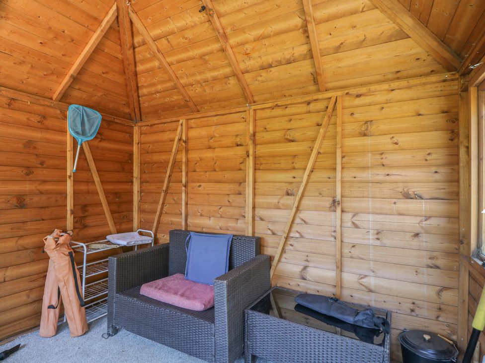 A snug with wooden walls and seating at Hedgehogs Lodge in South Molton