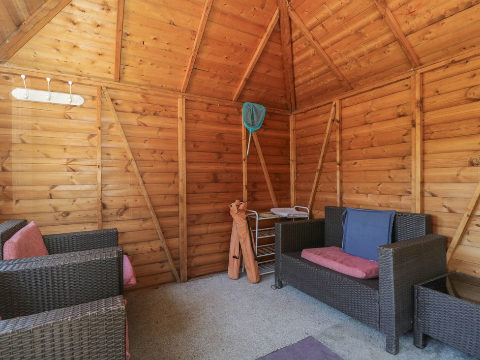 A garden shed with seating and storage at Hedgehogs Lodge in South Molton