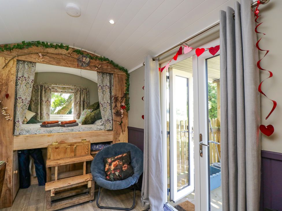 A bedroom with a bed and chair at Valley View Shepherd's Hut South Molton