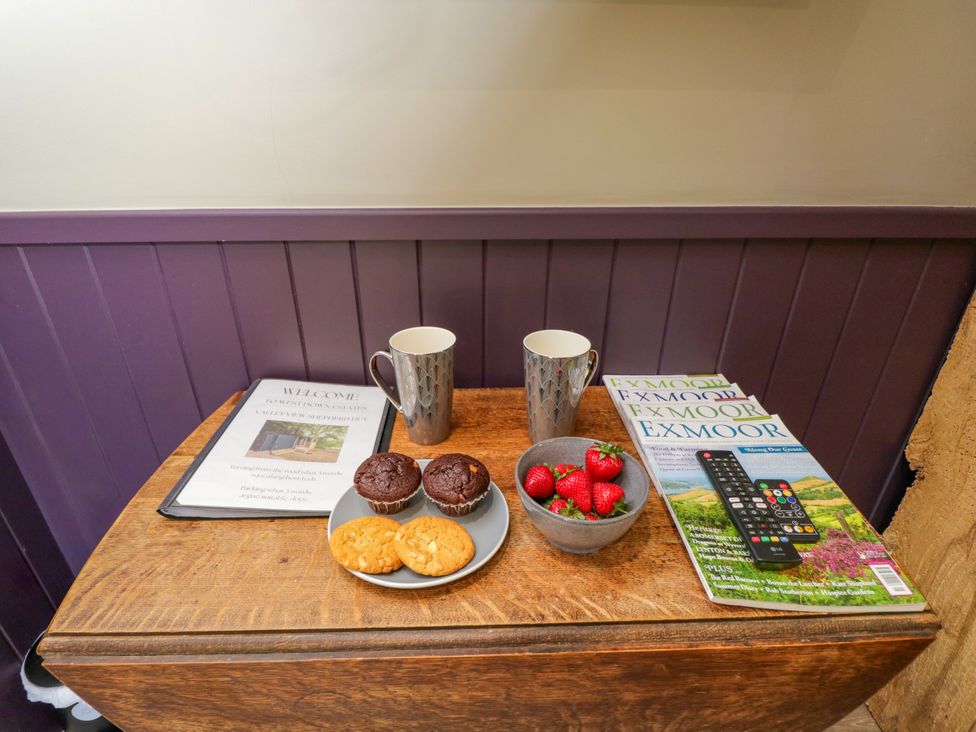 A table with welcome sign, coffee mug, snacks and magazine at Valley View Shepherd's Hut South Molton