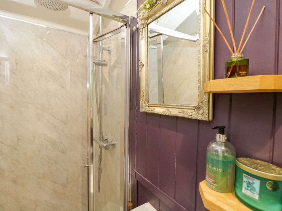 A shower with a mirror and shelves at Valley View Shepherd's Hut in South Molton