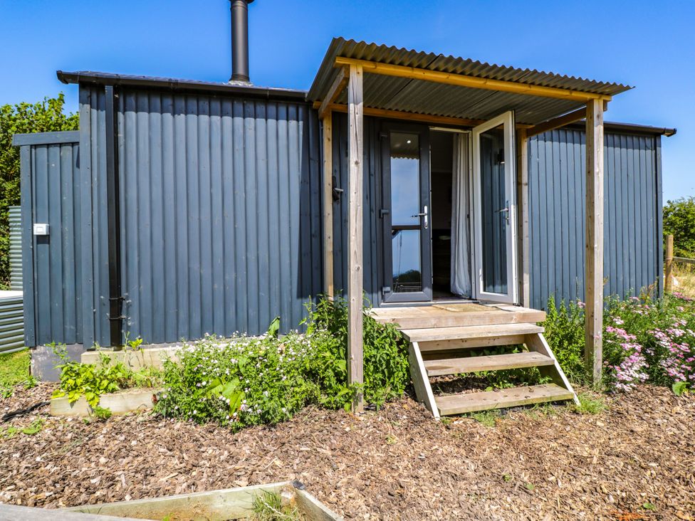 A hut with steps and flower beds at Hares Hideaway Shepherd's Hut South Molton