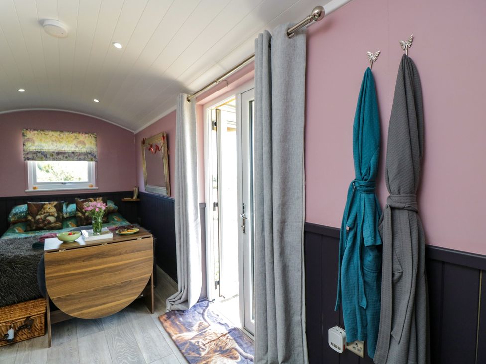 A living room with a bed and a door at Hares Hideaway Shepherd's Hut in South Molton