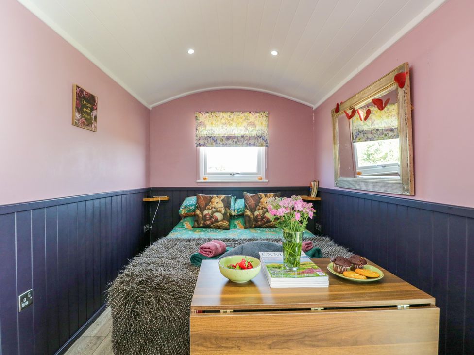 A bedroom with a bed and small table at Hares Hideaway Shepherd's Hut South Molton