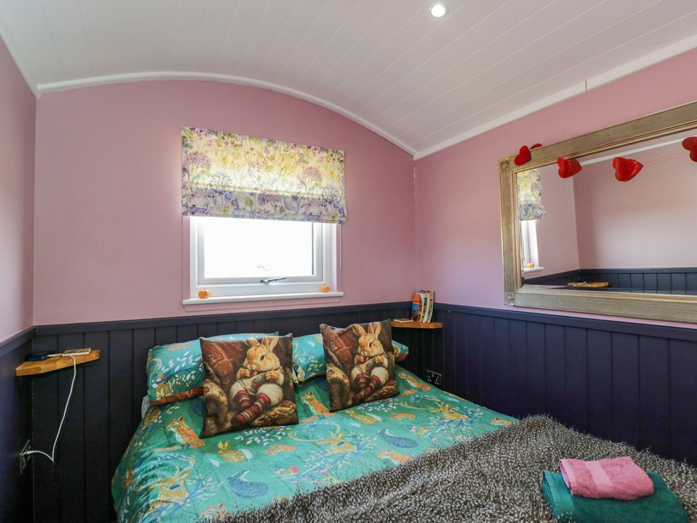 A bedroom with a bed and decorative pillows at Hares Hideaway Shepherd's Hut South Molton