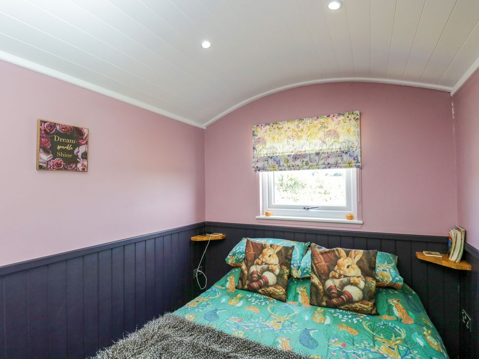 A bedroom with a bed and cushions at Hares Hideaway Shepherd's Hut South Molton