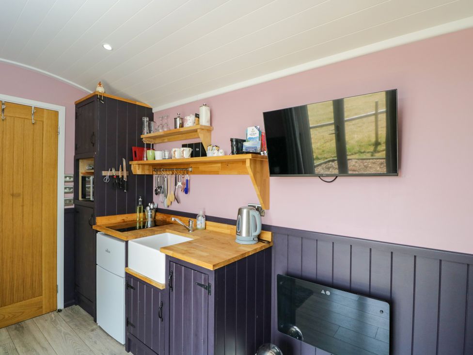A kitchen with a sink and shelves at Hares Hideaway Shepherd's Hut in South Molton