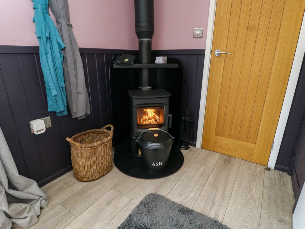 A snug with a wood stove and basket at Hares Hideaway Shepherd's Hut South Molton