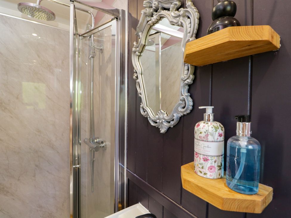 A bathroom with a shower and toiletries at Hares Hideaway Shepherd's Hut in South Molton