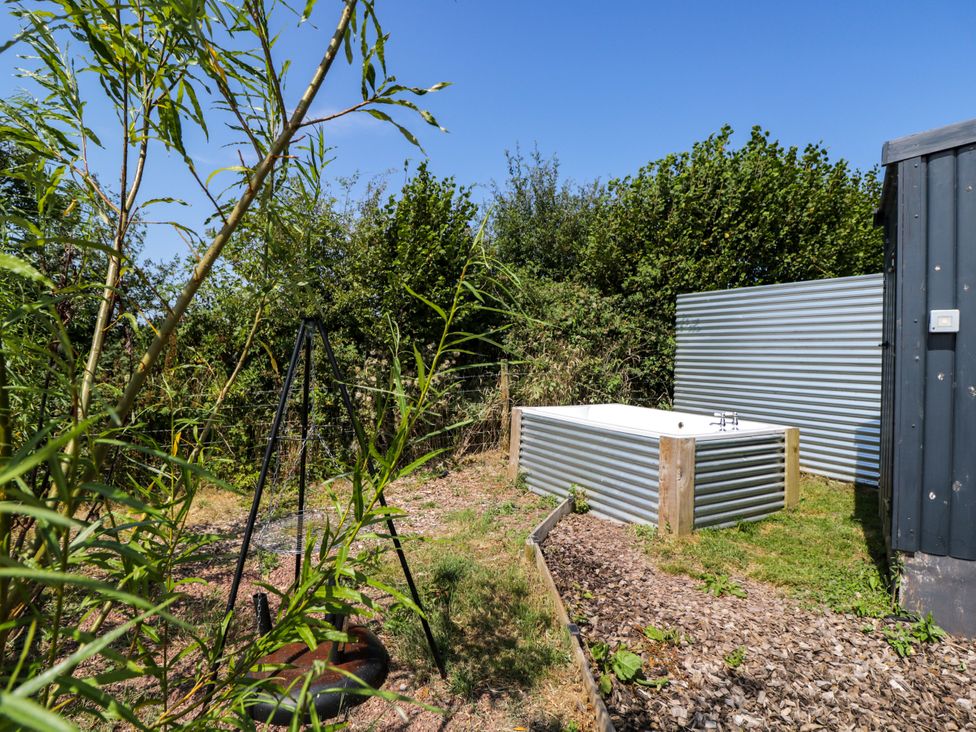 An outdoor area with a bathtub and swingset at Hares Hideaway Shepherd's Hut in South Molton