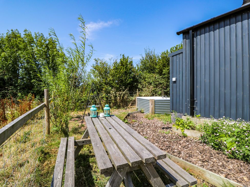 An outdoor seating area with a table and lanterns at Hares Hideaway Shepherd's Hut South Molton