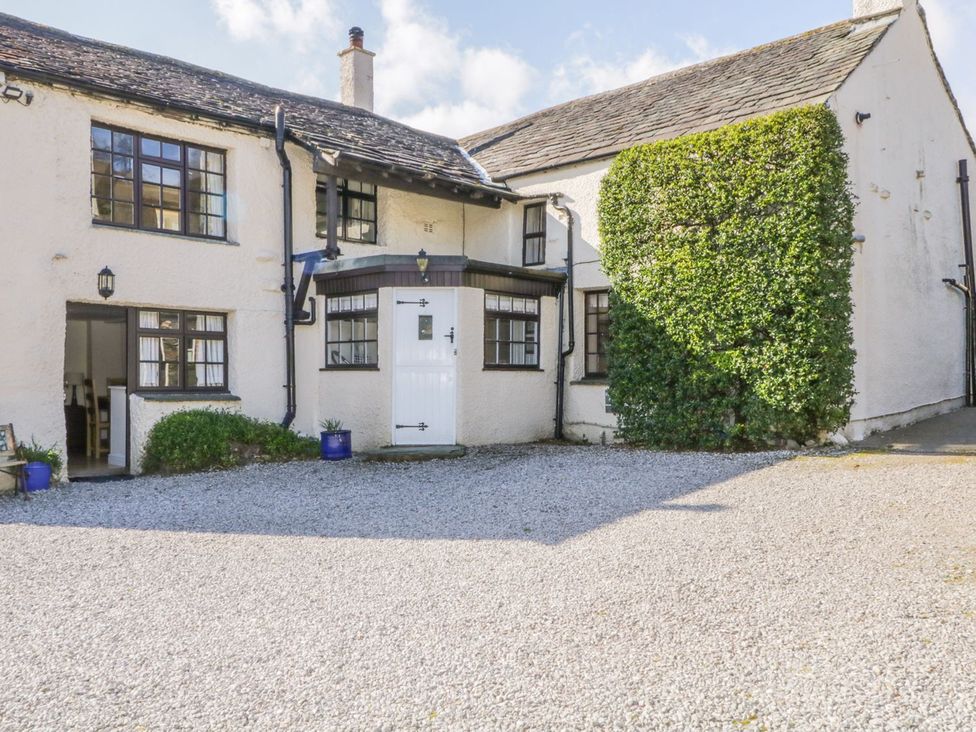 A view of a house with a gravel driveway and hedges at The Farmhouse in Keswick