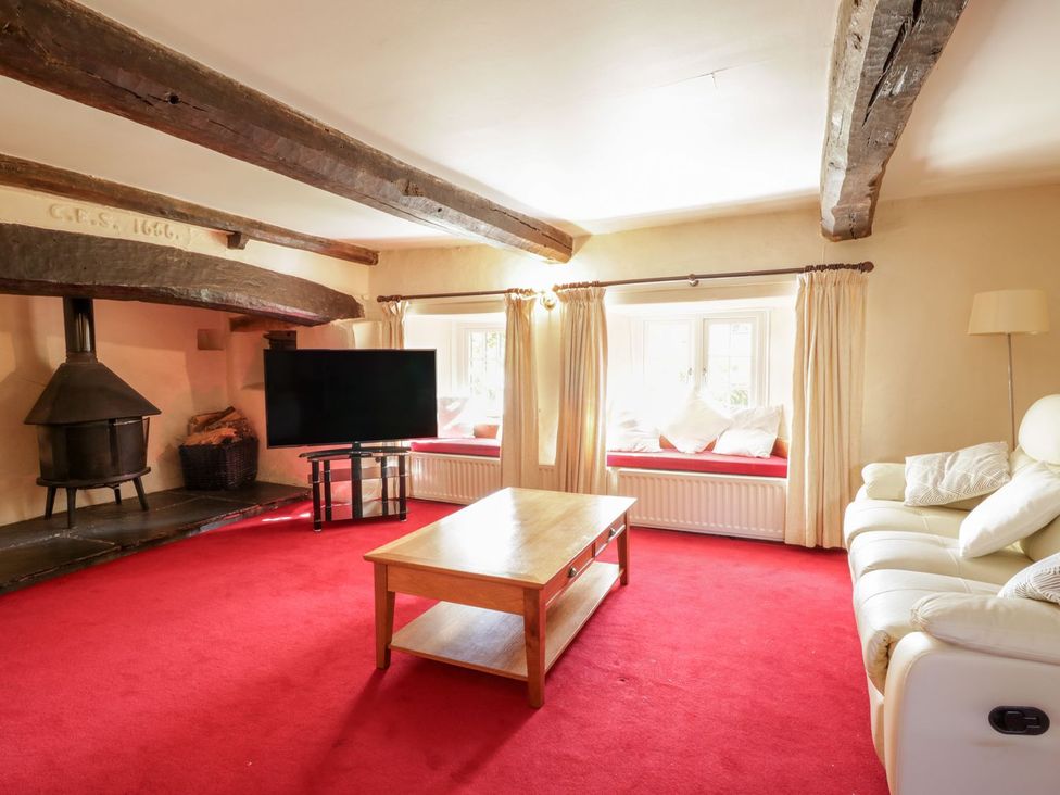 A living room with a fireplace and television at The Farmhouse in Keswick