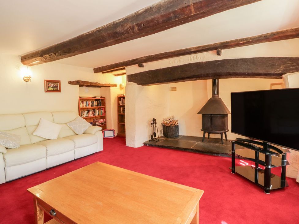 A living room with a sofa and bookshelf at The Farmhouse in Keswick