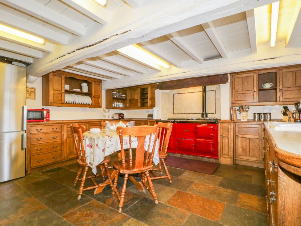 A kitchen with wooden cabinets and a red stove at The Farmhouse in Keswick