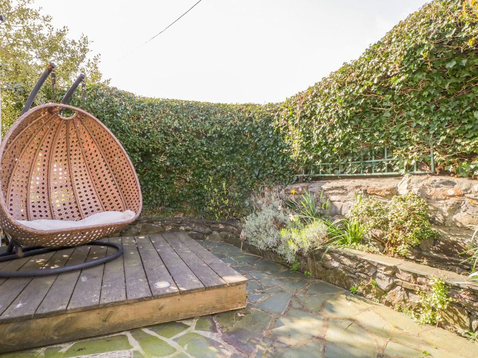 A garden with a hanging chair and stone wall at The Farmhouse in Keswick