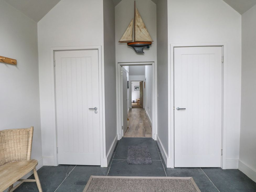 A hallway with two doors and a decorative sailboat at Wood Meadow in Helston