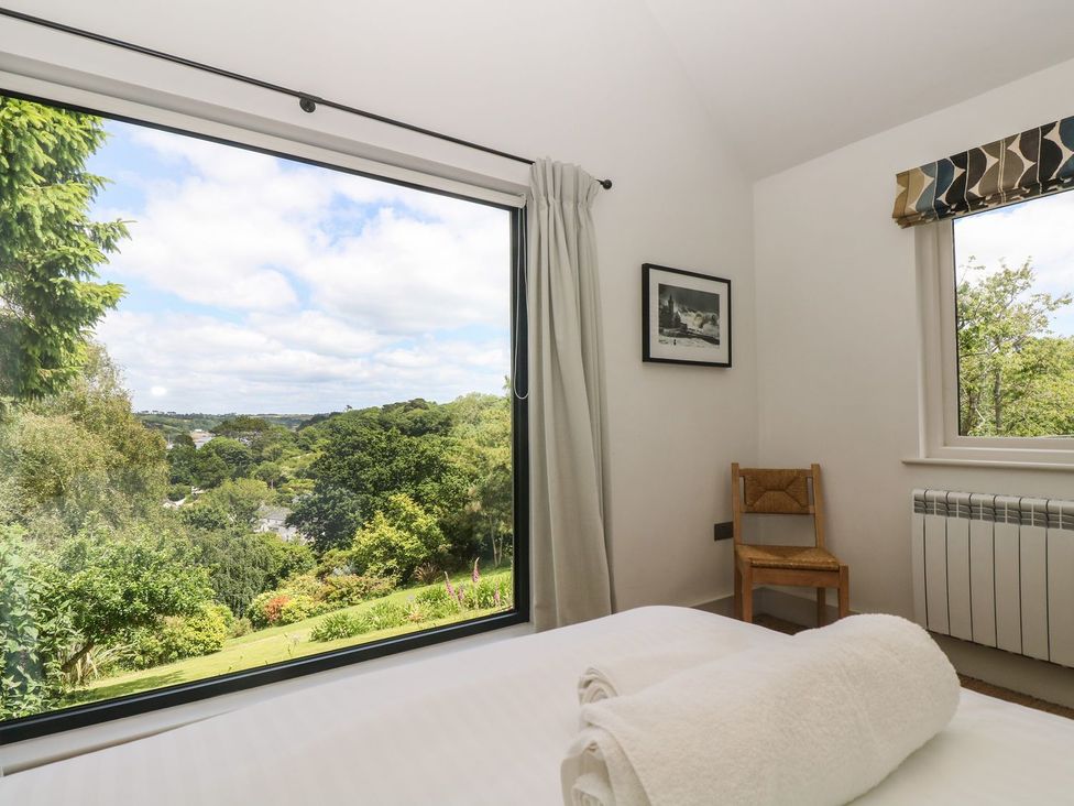 A bedroom with a view and a chair at Wood Meadow in Helston
