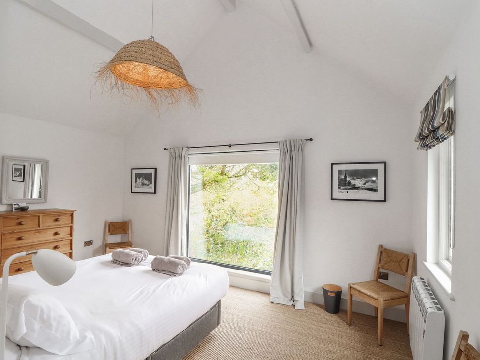 A bedroom with a bed and window at Wood Meadow in Helston