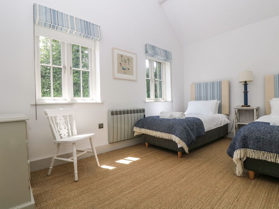 A bedroom with two beds and a chair at Wood Meadow Helston