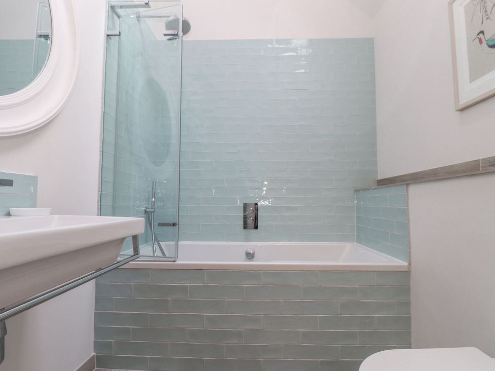 A bathroom with a sink, bathtub, shower and mirror at Wood Meadow in Helston